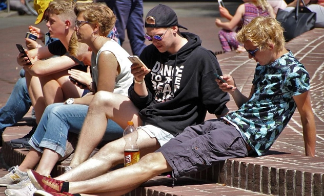060 - Jugendliche Smartphones Jugendliche mit Smartphones sitzen auf Brunnenabsatz