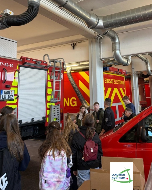 Zu sehen sind einige Jungen und Mädchen, sie sind in der Feuerwehrtechnischen Zentrale und schauen sich verschiedene Einsatzfahrzeuge der Feuerwehr an.