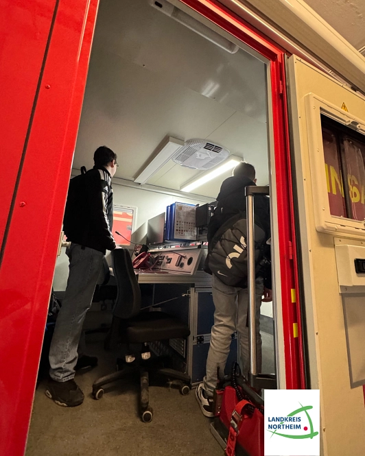 Zu sehen sind zwei Jungen, die in einem Einsatzfahrzeug der Feuerwehr stehen.