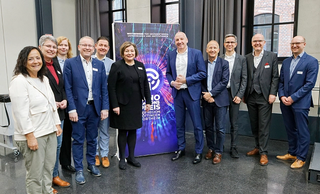 Auftaktveranstaltung Innovationspreis 2025 Eine Gruppe von zwölf Personen steht gemeinsam vor einem farbenfrohen Roll-up mit dem Schriftzug „Innovationspreis Region Göttingen Northeim“. Die Veranstaltung fand in einem modernen, lichtdurchfluteten Raum mit großen Fenstern statt. Die Teilnehmenden – Vertreterinnen und Vertreter aus Wirtschaft, Verwaltung und Institutionen – posieren gut gelaunt für ein Gruppenfoto. Alle sind geschäftlich gekleidet, einige tragen Namensschilder. Das Roll-up im Hintergrund verweist auf den Wettbewerb für Gründer*innen, Unternehmen und Institutionen aus der Region.