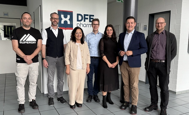 Besuch DFE Pharma Zu sehen sind sieben Personen die im Foyer des Unternehmens DFE Pharma stehen und in die Kamera schauen. Zu sehen sind (v.l.n.r.): Helge Lüttich (Fachkraft für Arbeitssicherheit), Dr. Georg Platz (Produktionsleiter), Astrid Klinkert-Kittel (Landrätin Landkreis Northeim), Gerhard Windecker (Werkleiter), Aniela Wucherpfennig (Personalleitung), Marcel Riethig (Landrat Landkreis Göttingen), Marcel Diederich (Geschäftsführer WRGN)