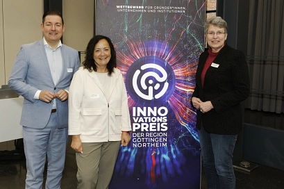 Der Göttinger Landrat Marcel Riethig, die Northeimer Landrätin Astrid Klinkert-Kittel und die Göttinger Oberbürgermeisterin Petra Broistedt stehen vor einem bunten Aufsteller mit der Aufschrift "Innovationspreis der Region Göttingen Northeim" und schauen freundlich in die Kamera.&nbsp;&copy;&nbsp;WRGN