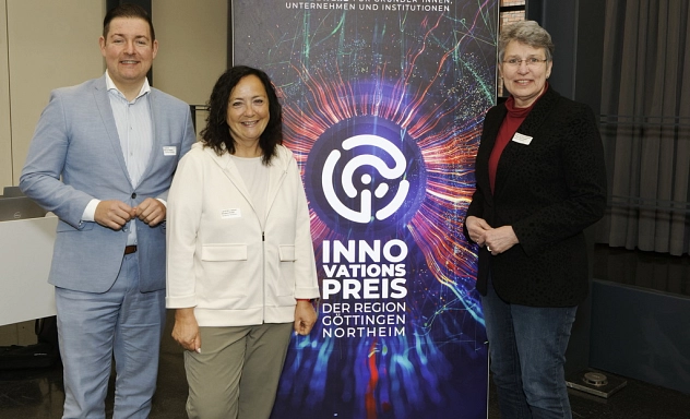 Bewerbungsstart Innovationspreis 2025 Der Göttinger Landrat Marcel Riethig, die Northeimer Landrätin Astrid Klinkert-Kittel und die Göttinger Oberbürgermeisterin Petra Broistedt stehen vor einem bunten Aufsteller mit der Aufschrift "Innovationspreis der Region Göttingen Northeim" und schauen freundlich in die Kamera.
