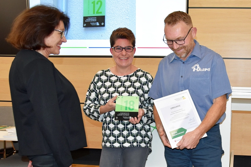 Ein Mann und eine Frauen haben gemeinsam eine Grüne Hausnummer erhalten.