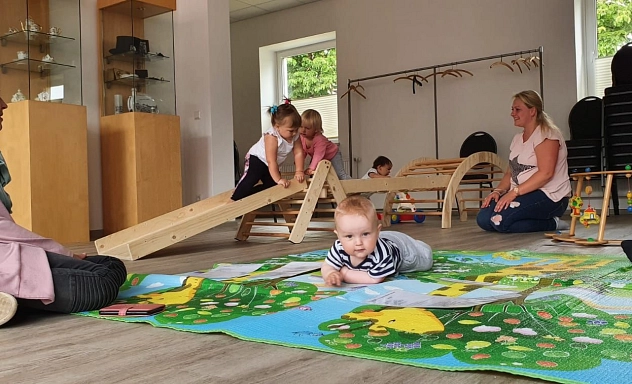 Das Bild zeigt spielende Kinder mit ihren Müttern und die Familienkrankenschwester Julia Burkhardt.