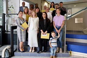Gruppenfoto auf einer Treppe im Foyer eines öffentlichen Gebäudes. Mehrere Erwachsene unterschiedlicher Herkunft stehen mit Urkundenmappen in den Händen für ein Erinnerungsfoto zusammen. Im Vordergrund steht ein kleines Kind. Die Gruppe blickt in die Kamera.&nbsp;&copy;&nbsp;Landkreis Northeim