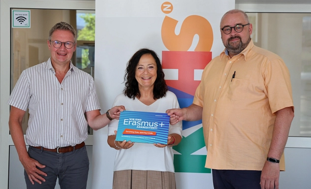 Erasmus+-Akkreditierung KVHS Northeim Drei Personen – zwei Männer und eine Frau – stehen vor einem Roll-up der Kreisvolkshochschule Northeim und halten gemeinsam ein Schild mit der Aufschrift ‚Wir sind Erasmus+ akkreditiert‘ in die Kamera. Das Foto entstand anlässlich der Erasmus+-Akkreditierung der KVHS.