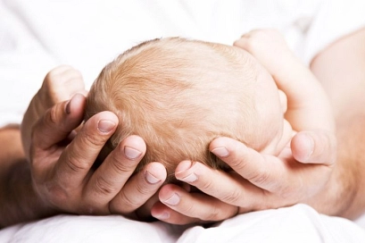 Man sieht den Kopf eines Babys, der sanft in den Händen des Vaters liegt.&nbsp;&copy;&nbsp;istock/Lloret