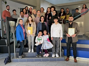 Eine Gruppe neu eingebürgerter Menschen steht auf der Treppe im Eingangsbereich des Kreishauses Northeim. Vorne sind mehrere Kinder und Erwachsene zu sehen, einige halten ihre Einbürgerungsunterlagen in den Händen. Die Gruppe lächelt in die Kamera. Im Hintergrund erkennt man das Treppengeländer, Teile des Foyers und eine Wandtafel des Landkreises Northeim.&nbsp;&copy;&nbsp;Landkreis Northeim