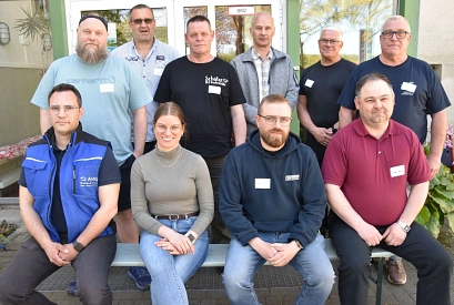 Gruppenfoto von zehn Teilnehmenden einer Hausmeisterschulung vor einem Gebäude. Vier Personen sitzen vorne auf einer Bank, sechs stehen dahinter. Die Gruppe trägt Alltags- und Arbeitskleidung, mehrere Personen haben Namensschilder.&nbsp;&copy;&nbsp;Landkreis Northeim