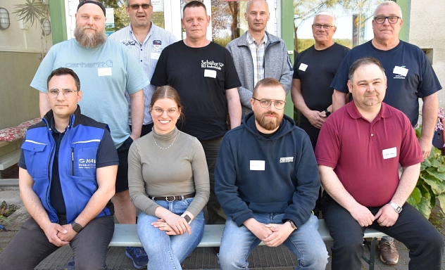 Hausmeisterschulung 2026 Gruppenfoto von zehn Teilnehmenden einer Hausmeisterschulung vor einem Gebäude. Vier Personen sitzen vorne auf einer Bank, sechs stehen dahinter. Die Gruppe trägt Alltags- und Arbeitskleidung, mehrere Personen haben Namensschilder.