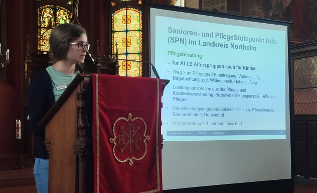 Lara Birresborn Vortrag Zu sehen ist eine Mitarbeiterin des Senioren-und Pflegestützupunktes des Landkreis Northeim die einen Vortrag in einer Kirche hält.