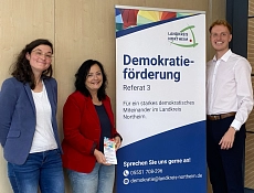 Referat 3 Demokratieförderung Zu sehen sind v.l.n.r. Dr Katharina Trittel (Projektkoordinatorin R3), Landrätin Astrid Klinkert-Kittel, ein Roll-Up mit dem Titel Referat 3 - Demokratieförderung und Christian Ulmitz, Leiter Referat 3.