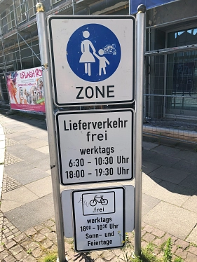 Verkehrsschild am Eingang einer Fußgängerzone. Das Schild kennzeichnet den Bereich als Fußgängerzone und enthält Zusatzschilder mit Regelungen für den Lieferverkehr sowie für den Radverkehr zu bestimmten Zeiten. Im Hintergrund sind ein Gebäude mit Baugerüst und ein Gehweg zu sehen.&nbsp;&copy;&nbsp;Landkreis Northeim