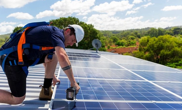 Ein Installateur installiert Solaranlagen auf dem Dach