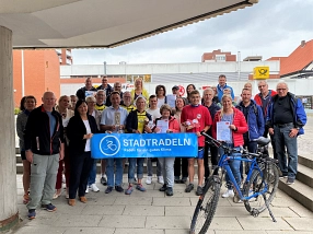 Zu sehen ist eine Gruppe von ca. 30 Personen, die vor dem Kreishaus stehen und für ein Foto posieren. Sie halten ein Banner mit der Aufschrift "Stadtradeln". Rechts im Bild steht ein Fahrrad vor der Gruppe.&nbsp;&copy;&nbsp;Landkreis Northeim