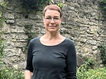 Zu sehen ist die Mitarbeiterin des Landkreises Veronika Strunk im Portrait, sie steht draußen vor einer Mauer.