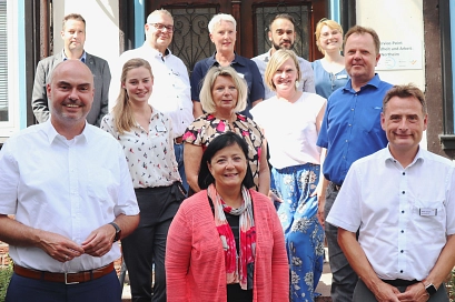 Zu sehen ist eine Gruppe von 12 Personen, die bei der Eröffnung des Service-Points Gesundheit und Arbeit des Jobcenters Landkreis Northeim anwesend waren. Zu sehen sind unter anderem Landrätin Astrid Klinkert-Kittel, Dezernent Harald Rode, Stefan Schäfer,&nbsp;&copy;&nbsp;Jobcenter Landkreis Northeim