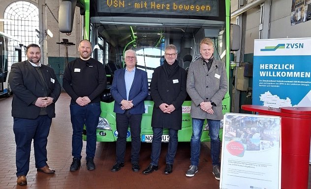 ZVSN Automatische Fahrgastzählsysteme Fünf Männer stehen in einer Werkhalle vor einem grünen Linienbus des Verkehrsverbunds VSN bei einem offiziellen Termin.